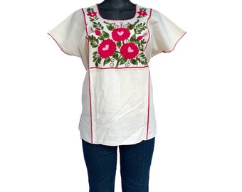 May include: White cotton blouse with short sleeves and a red embroidered floral design on the front.