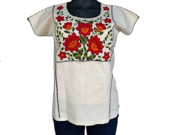 May include: White cotton blouse with short sleeves and a floral embroidery design in red, orange, and green.