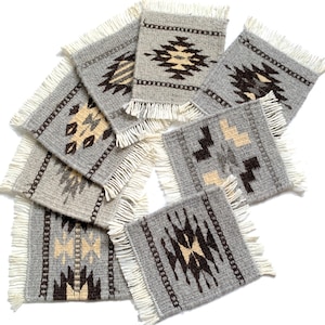 May include: A collection of gray woven coasters with geometric patterns in black and beige. Each coaster has a fringed edge. The coasters are arranged on a white background.