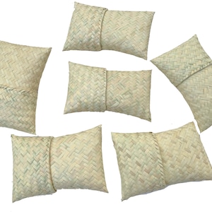 May include: Six woven straw pillows in a variety of sizes and shapes. The pillows are all a light beige color and have a woven pattern.