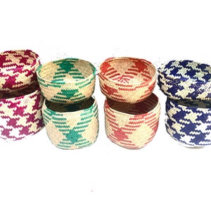 May include: Six woven baskets with a geometric pattern. The baskets are in four colours: red, green, blue, and purple. The baskets are stacked on top of each other.