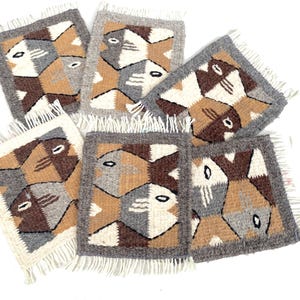 May include: Set of six woven wool coasters featuring a geometric pattern of stylized fish in shades of brown, gray, and beige. Each coaster has a fringe border.
