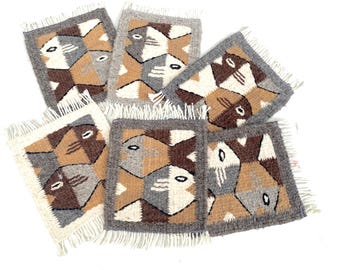 May include: Set of six woven wool coasters featuring a geometric pattern of stylized fish in shades of brown, gray, and beige. Each coaster has a fringe border.