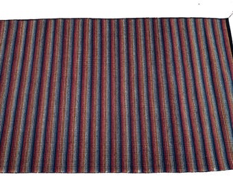 May include: A striped rug with a variety of colors, including red, blue, and white. The rug has a woven texture and is made of a durable material.