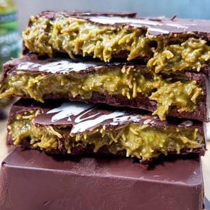 May include: A stack of four chocolate bars with a green filling. The bars are broken open, revealing the green filling. The filling is a light green color and has a stringy texture.