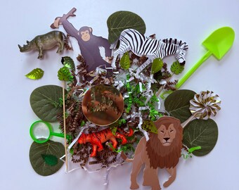 May include: A collection of jungle-themed decorations, including a zebra, lion, monkey, and rhino figurines. Green leaves, a green shovel, and a gold-colored circle with text are also included. The arrangement is set against a white background.