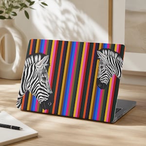 May include: A laptop skin featuring a vibrant vertical striped pattern in shades of blue, yellow, pink, orange, and black. Two black and white zebra heads are positioned on the left and right sides, facing inward toward the center of the laptop.