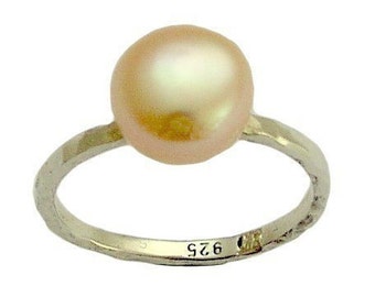 May include: A delicate ring with a single, large, round, light pink pearl. The ring is made of silver and has a 925 stamp on the band.