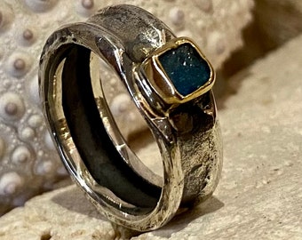 May include: A silver ring with a textured band and a square blue gemstone set in gold.