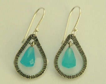 May include: A pair of silver teardrop earrings with a turquoise gemstone in each. The earrings have a textured, hammered finish.