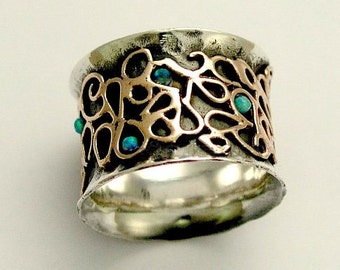 May include: A silver and rose gold ring with a wide band and intricate design. The band is decorated with a swirling pattern and set with turquoise gemstones.