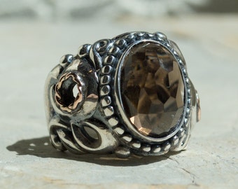 May include: A silver ring with a large, faceted, brown gemstone set in a detailed, ornate design.