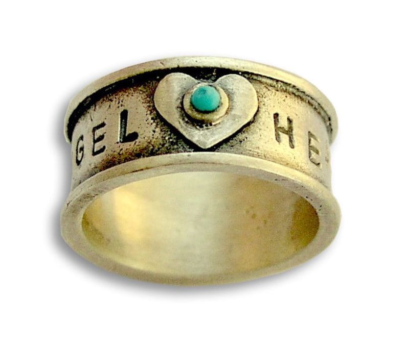 May include: A silver ring with a heart-shaped design and a turquoise stone. The ring is engraved with the words "Angel" and "Heart".