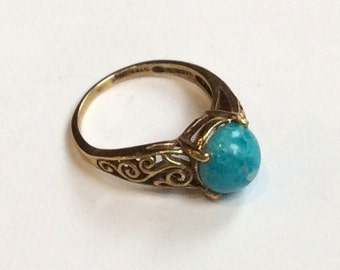 May include: A gold ring with a turquoise stone set in a filigree design.