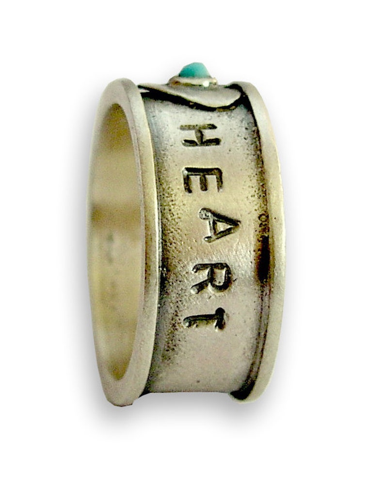 May include: A silver ring with a turquoise stone and the word "HEART" engraved on the band.