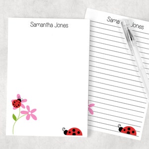 May include: White personalized stationery featuring the name "Samantha Jones" at the top. The design includes a ladybug and pink flower graphic. A lined notepad and a pen are also visible.