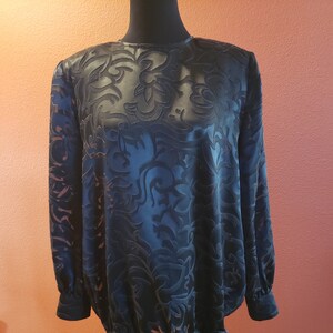 Könnte beinhalten: Eine schwarze Bluse mit langen Ärmeln und einem Blumenmuster. Die Bluse hat einen Knoten in der Taille.