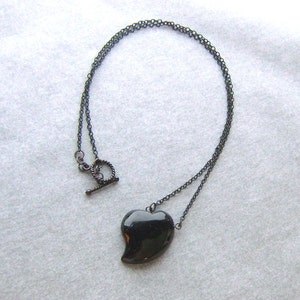 May include: A black heart-shaped pendant necklace with a black chain and a lobster clasp.