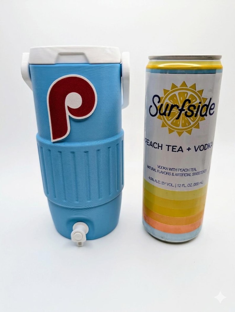 May include: A light blue beverage cooler with a white lid, handle, and spigot, featuring a red and white P logo. Next to it is a 12 fl. oz. Surfside Peach Tea + Vodka can with a yellow sun graphic, white background, and horizontal color stripes.