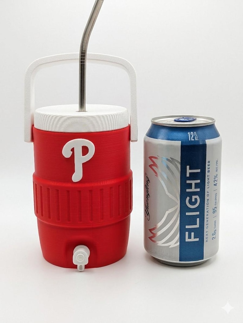 May include: A red and white plastic beverage cooler with a white handle, a white lid, and a white spigot, featuring a white letter P logo on the front. A silver metal straw protrudes from the top. Next to it is a 12 fluid ounce aluminum beer can.