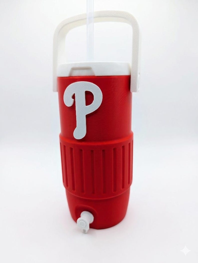 May include: A red insulated beverage cooler with a white handle and a white lid. The cooler features a prominent white letter P logo on the front and a small white spigot at the base. A clear plastic straw extends from the top of the lid.