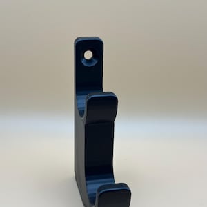 May include: A black plastic hook with a single hole for mounting. The hook is designed to hold items like coats, hats, or bags.
