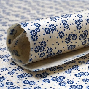 May include: A roll of white wrapping paper with a blue floral pattern. The paper is rolled up and the end is visible.
