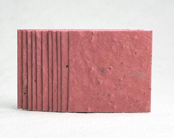 May include: A stack of 10 pink plantable seed paper cards. The paper has a textured, speckled appearance.