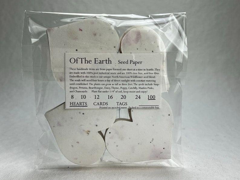 以下が含まれることがあります： 前面に「Of The Earth Seed Paper」と印刷された白いハート型の種紙の包装。パッケージには、8、10、12、16、20、24、100個のハートが含まれています。