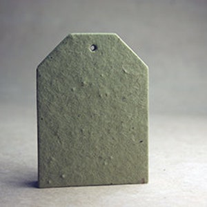May include: A single, olive-green tag with a textured surface and a small hole at the top. The tag has a rectangular shape with a pointed top, and it stands upright against a neutral background.