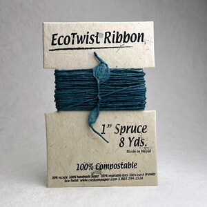 May include: A spool of dark teal EcoTwist Ribbon wrapped around a light tan paper card. The card features the text EcoTwist Ribbon, 1&rdquo; Spruce, 8 Yds., Made in Nepal, and 100% Compostable. The ribbon has a textured, twisted appearance.