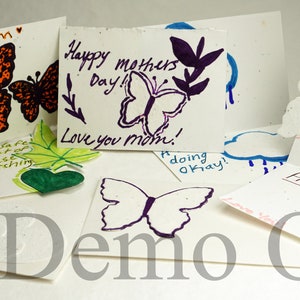May include: Assortment of handmade greeting cards featuring butterfly designs and handwritten messages. The cards are made of seed paper, which can be planted to grow flowers. The messages include "Stay Warm", "Happy Mothers Day! Love you mom!", "Happy Birthday", and "Hope you had a lot of fun planning these cards and watching them grow!"