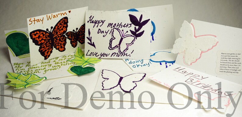 May include: Assortment of handmade greeting cards featuring butterfly designs and handwritten messages. The cards are made of seed paper, which can be planted to grow flowers. The messages include "Stay Warm", "Happy Mothers Day! Love you mom!", "Happy Birthday", and "Hope you had a lot of fun planning these cards and watching them grow!"
