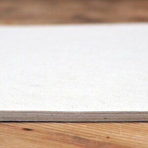 May include: A stack of white paper sheets on a wooden surface.