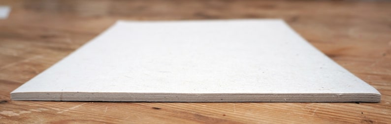 May include: A stack of white paper sheets on a wooden surface.