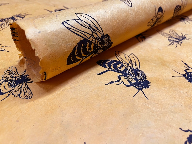 May include: A roll of brown wrapping paper with a repeating pattern of black bees. The paper has a textured, handmade look.