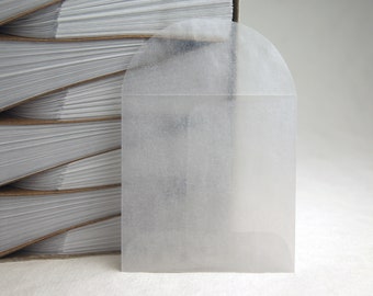 May include: A white, semi-transparent, envelope-style, self-adhesive, mailing label with a rounded top.