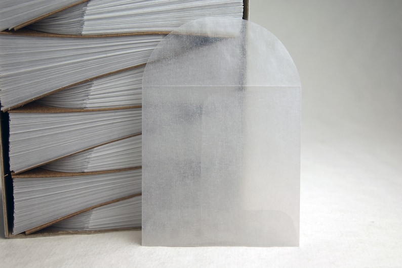 May include: A white, semi-transparent, envelope-style, self-sealing, paper bag with a rounded top.