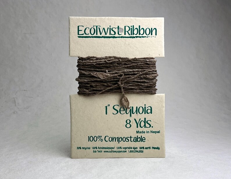 May include: A spool of dark brown EcoTwist Ribbon wrapped around a cream-colored paper card. The card features the text EcoTwist Ribbon, 1 inch Sequoia, 8 Yds., Made in Nepal, and 100% Compostable. The ribbon has a textured, twisted appearance.