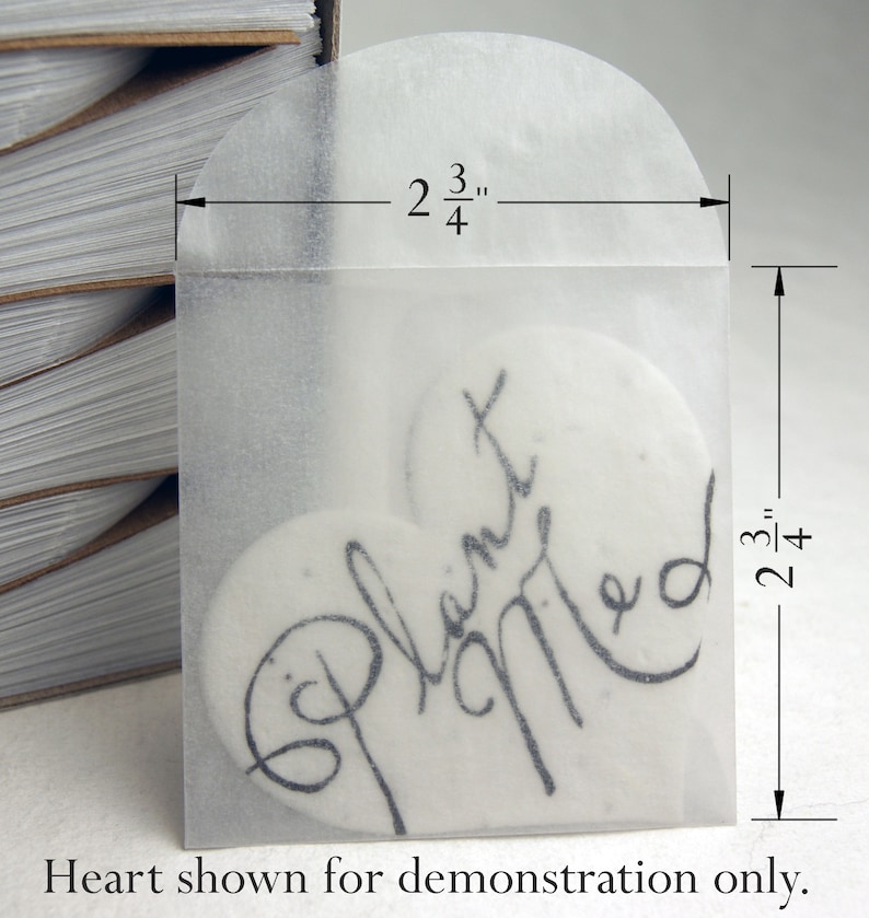 May include: A clear heart-shaped envelope with a white heart inside. The heart has the words "Planted" and "Married" written on it. The envelope is 2 3/4 inches wide and 2 3/4 inches tall.