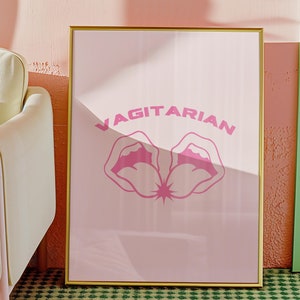 Peut inclure: Une affiche encadrée dorée avec un fond rose et le mot "VAGITARIAN" en lettres roses. L'affiche présente un graphique rose de deux lèvres avec une étoile au centre.