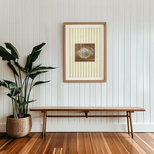 a green and white striped poster has a brown square with a pink border. In the square is a vintage white conch seashell image. The print is minimalist, beachy, with an east coast aesthetic. Great for bedroom or bathroom decor.