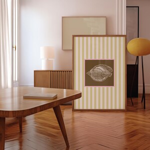 a green and white striped poster has a brown square with a pink border. In the square is a vintage white conch seashell image. The print is minimalist, beachy, with an east coast aesthetic. Great for bedroom or bathroom decor.