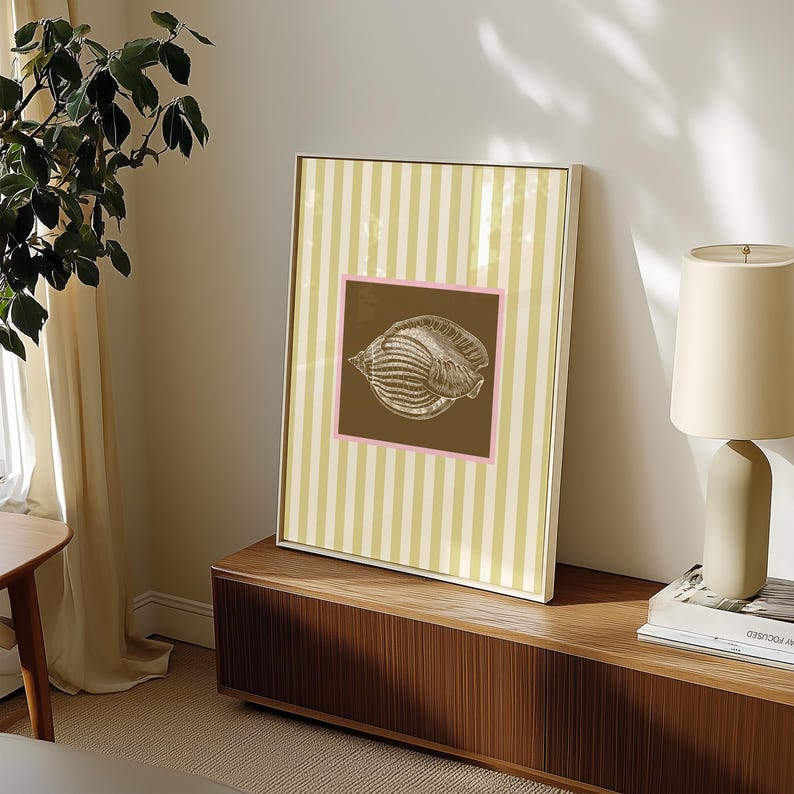 a green and white striped poster has a brown square with a pink border. In the square is a vintage white conch seashell image. The print is minimalist, beachy, with an east coast aesthetic. Great for bedroom or bathroom decor.
