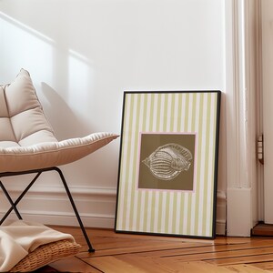 a green and white striped poster has a brown square with a pink border. In the square is a vintage white conch seashell image. The print is minimalist, beachy, with an east coast aesthetic. Great for bedroom or bathroom decor.
