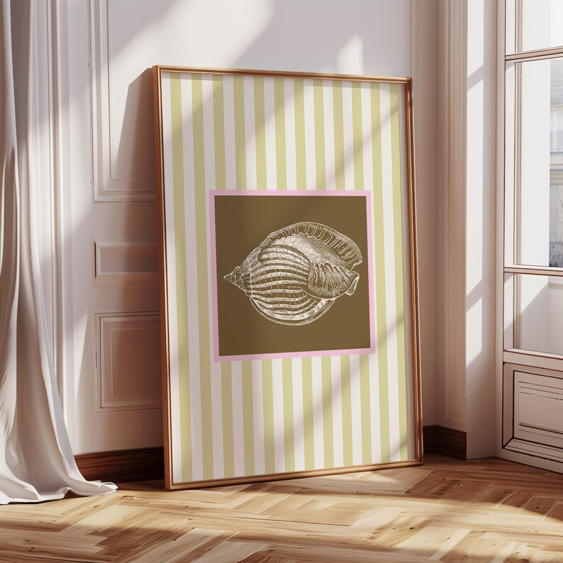 a green and white striped poster has a brown square with a pink border. In the square is a vintage white conch seashell image. The print is minimalist, beachy, with an east coast aesthetic. Great for bedroom or bathroom decor.