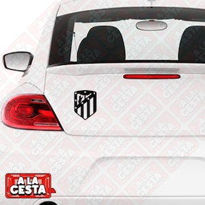 Peut inclure: Une voiture blanche avec un autocollant de logo d'équipe de football noir et blanc sur la vitre arrière. Le logo est un bouclier avec des rayures et une étoile. Le texte "ALA CESTA" est sur un autocollant rouge et blanc dans le coin inférieur gauche de l'image.