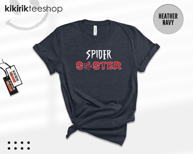 Puede incluir: Camiseta azul marino jaspeado con las palabras "SPIDER SISTER" en letras blancas y rojas. Un gr&aacute;fico de telara&ntilde;a est&aacute; entre las palabras. La camiseta es de Kikirikiteeshop.