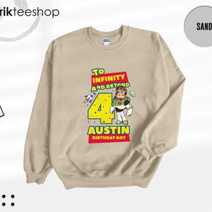 Puede incluir: Una sudadera de cuello redondo color arena con un estampado gr&aacute;fico que incluye el texto To Infinity and Beyond, el n&uacute;mero 4 y el nombre Austin. El dise&ntilde;o muestra un personaje de guardi&aacute;n espacial con cara de ni&ntilde;o y un cohete.
