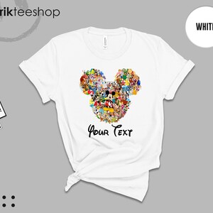 Pu&ograve; includere: T-shirt bianca con un colorato design a forma di testa di Topolino composto da vari personaggi dei cartoni animati. Il testo "Your Text" &egrave; stampato sotto. La maglietta ha maniche corte e girocollo.
